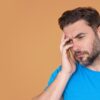 Homem com a mão sobre a cabeça representando alguém cansado ou estressado