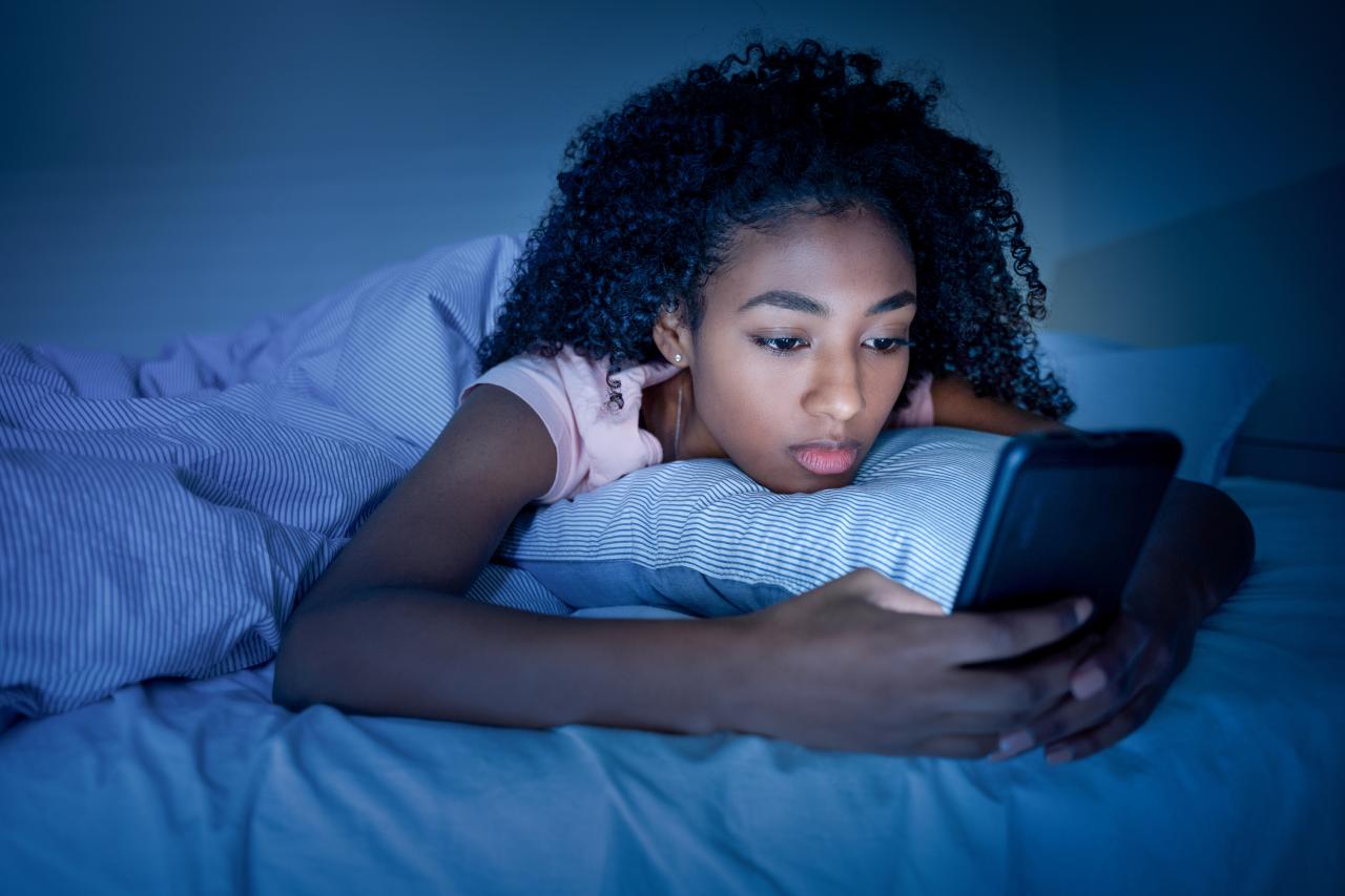 Imagem de pessoa usando celular deitada na cama