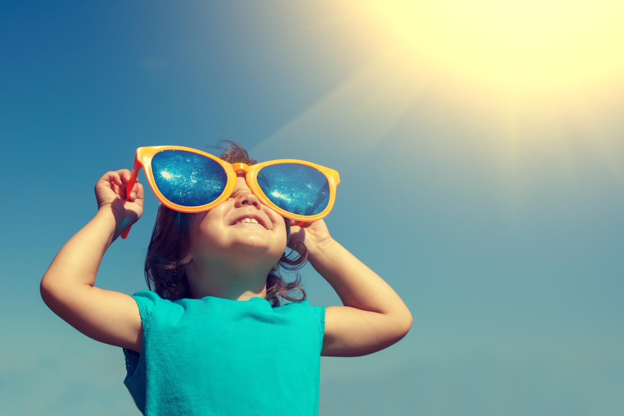 Imagem de criança de óculos escuro se protegendo do sol