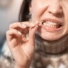 Imagem de pessoa limpando entre os dentes com um palito de madeira