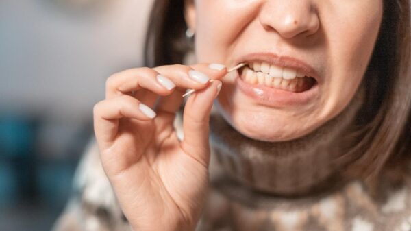 Imagem de pessoa limpando entre os dentes com um palito de madeira