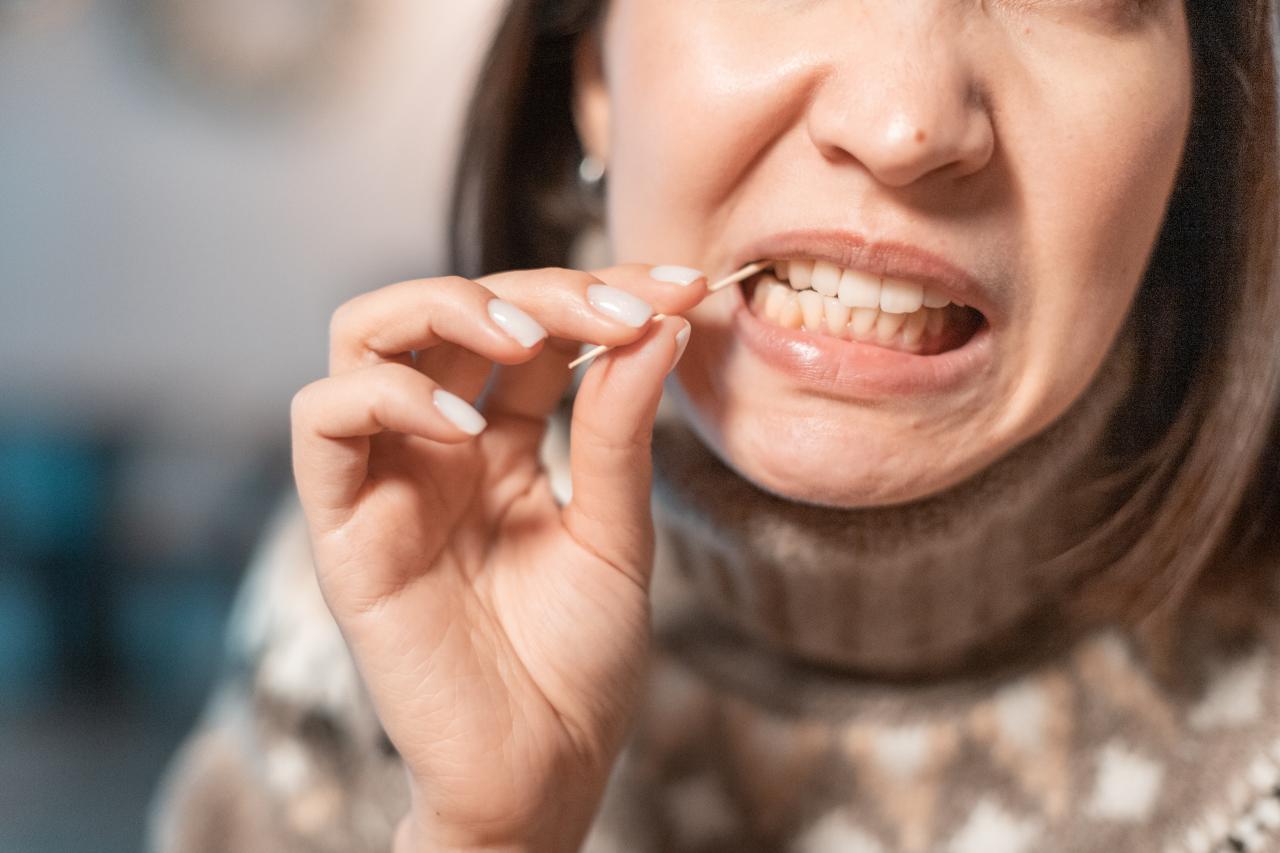 Imagem de pessoa limpando entre os dentes com um palito de madeira