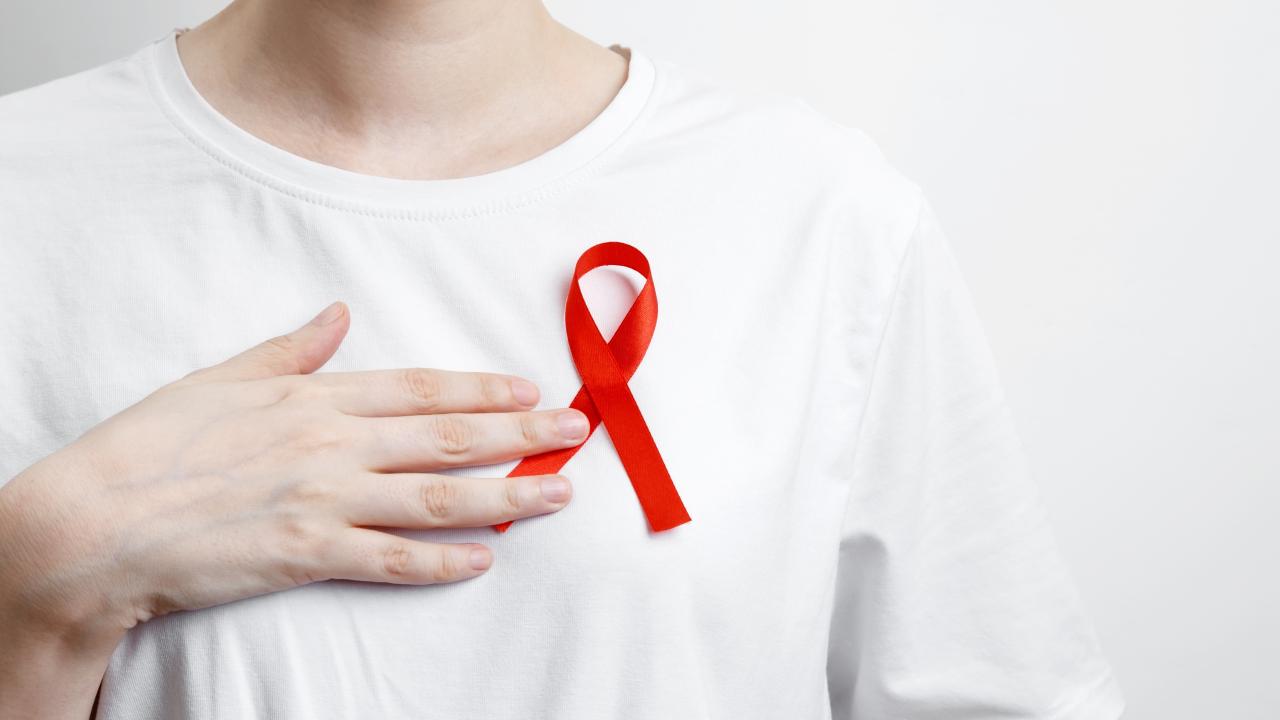 Imagem de pessoa vestindo uma camisa com o símbolo em formato de laço que representa o 'Dezembro vermelho'