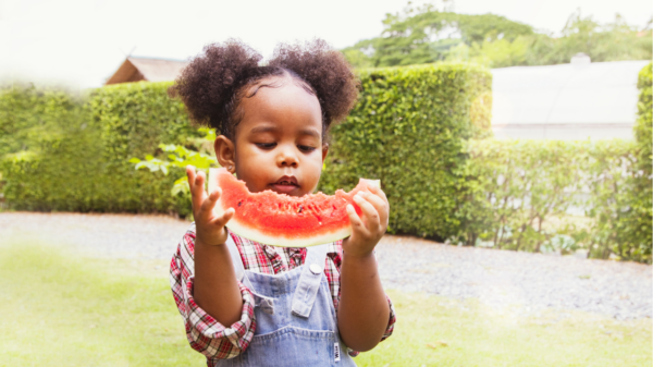 Imagem de menina comendo melancia no verão