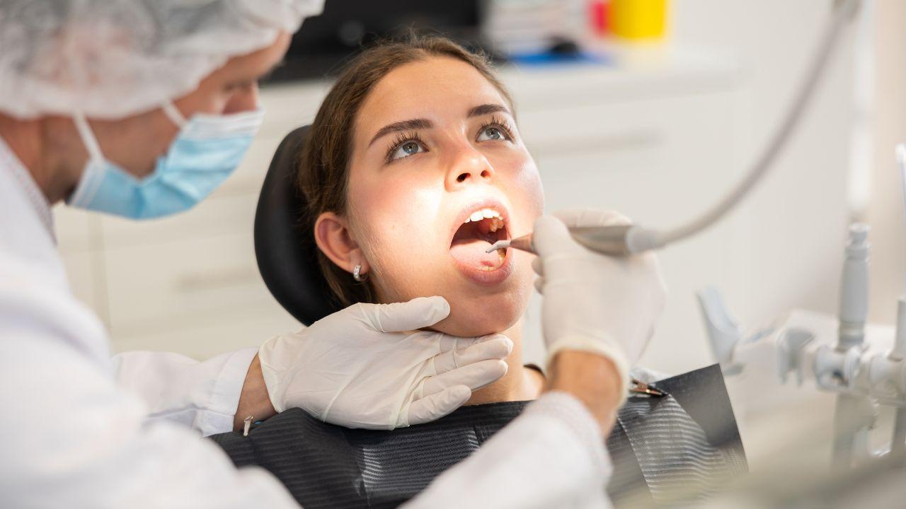 Mulher com a boca aberta em exame no dentista.