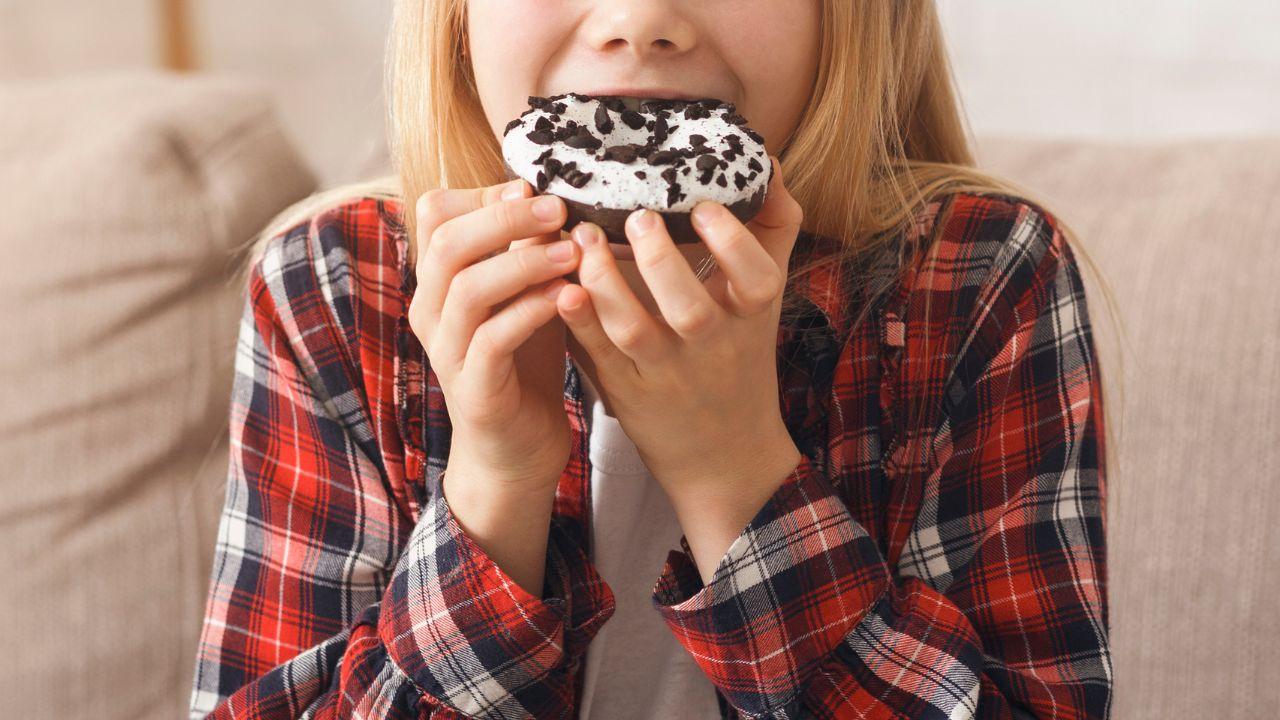 Imagem de uma criança comendo um donuts