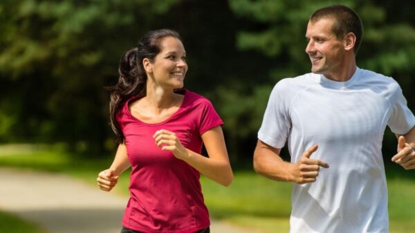Homem e mulher correndo juntos no parque, exercícios físicos são aliados na prevenção da demência