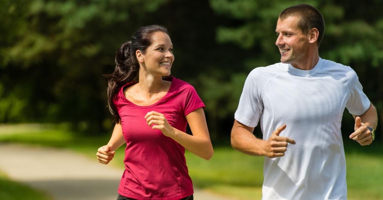Homem e mulher correndo juntos no parque, exercícios físicos são aliados na prevenção da demência