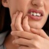 Imagem de uma pessoa com a mão no maxilar sentindo dor de dente