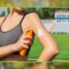 Mulher jovem aplicando protetor solar no braço ao ar livre