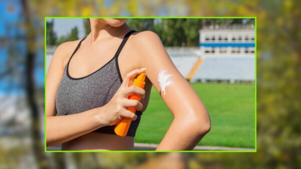 Mulher jovem aplicando protetor solar no braço ao ar livre