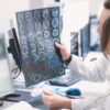 Foto mostra uma médica e um médico olhando para o computador e um exame de raio x.