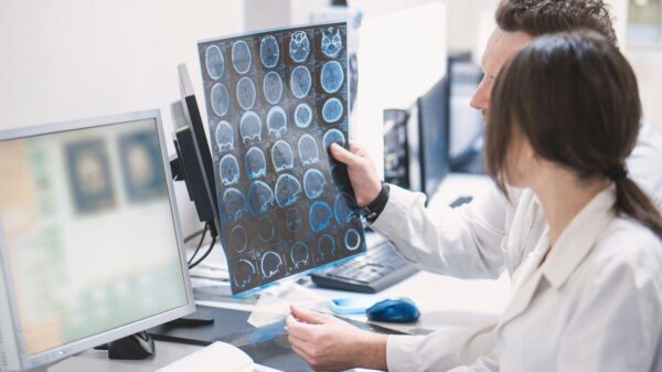 Foto mostra uma médica e um médico olhando para o computador e um exame de raio x.