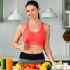 Mulher na frente da mesa com frutas e legumes.
