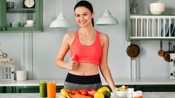 Mulher na frente da mesa com frutas e legumes.