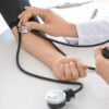 Médica aferindo a pressão do braço do paciente.