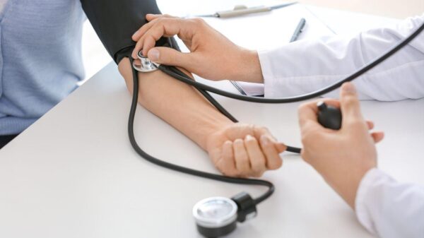 Médica aferindo a pressão do braço do paciente.