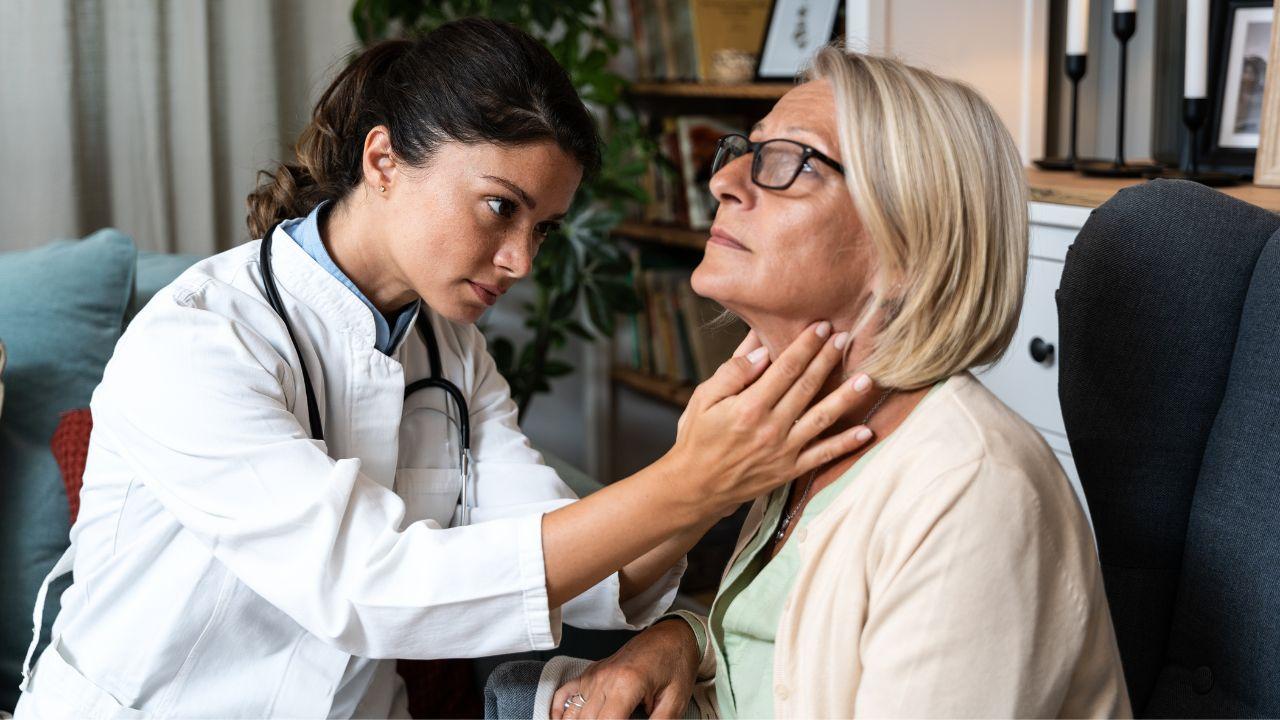 Mulher idosa sentada no consultório em frente a uma médica.