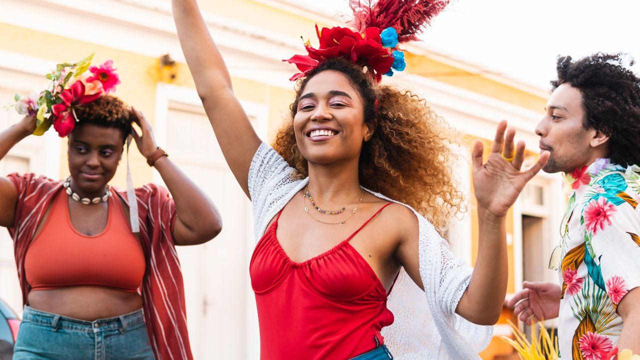 Imagem de duas mulheres e um homem sorrindo pulando Carnaval