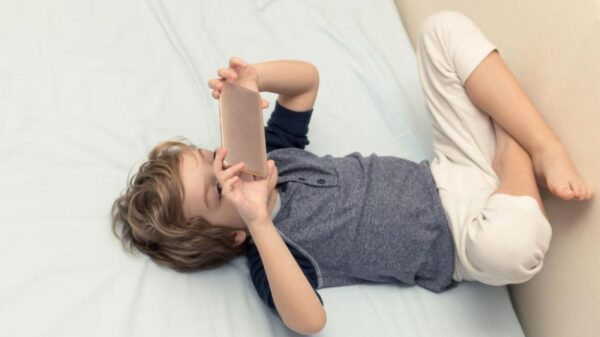 Criança usando dispositivo móvel em casa ilustra discussão sobre uso de telas na infância após novo guia da Academia Americana de Pediatria.