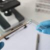 Imagem de mãos passando um cotonete em um canudo de laboratório para fazer um exame