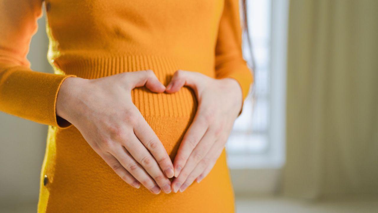 Imagem de uma mulher fazendo coração na barriga