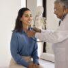 Mulher sentada na maca médica enquanto um médico homem a examina.