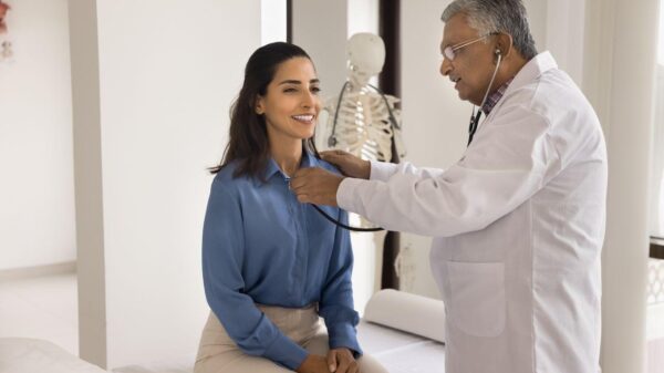 Mulher sentada na maca médica enquanto um médico homem a examina.