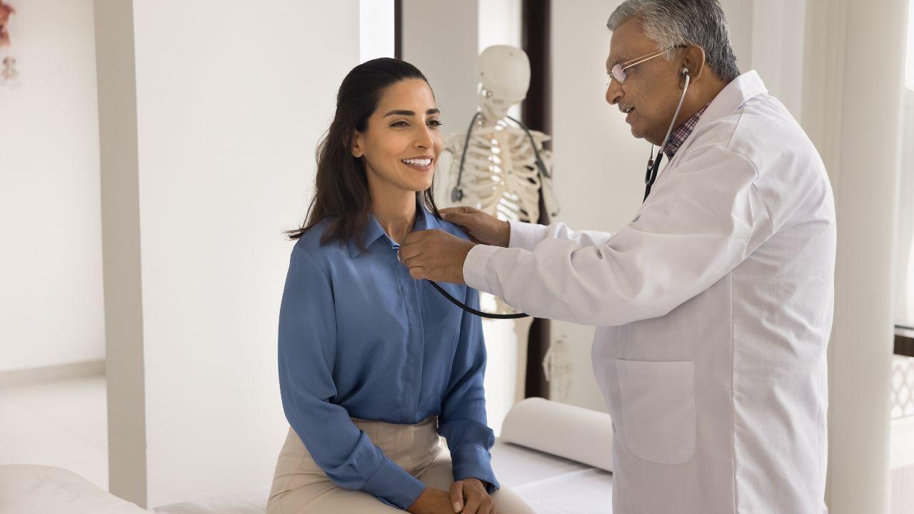 Mulher sentada na maca médica enquanto um médico homem a examina.