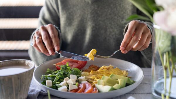 Pessoa comendo prato de salada em cima de uma mesa.