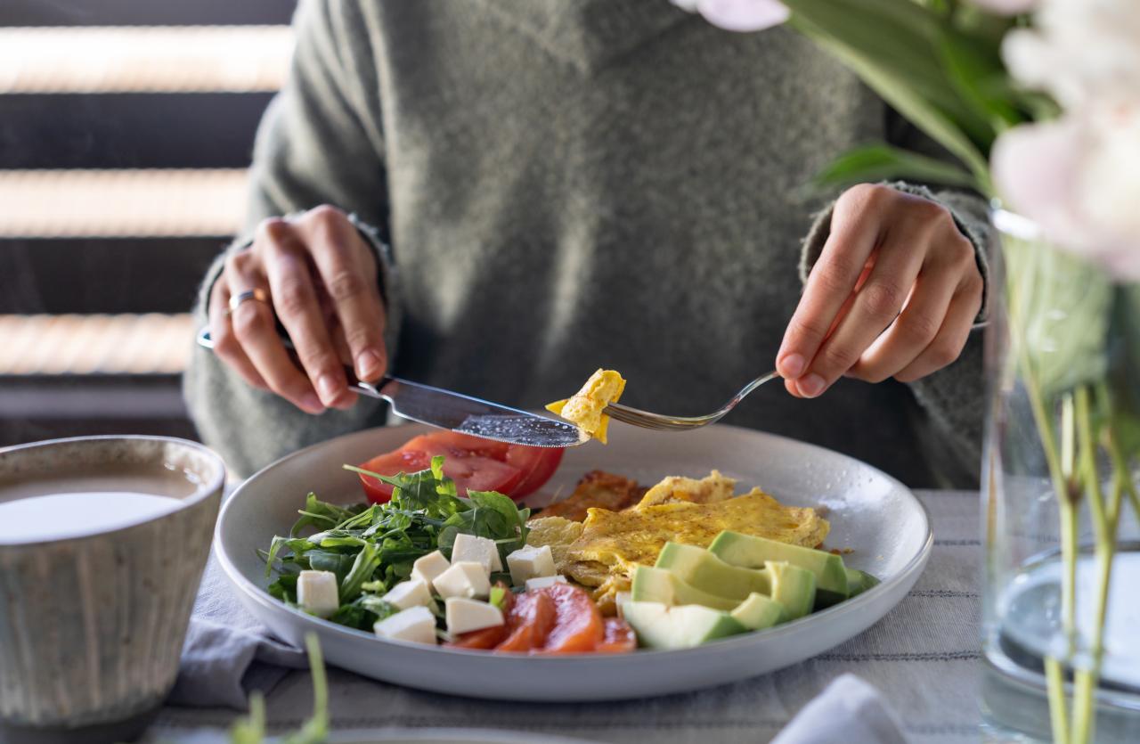 Pessoa comendo prato de salada em cima de uma mesa.