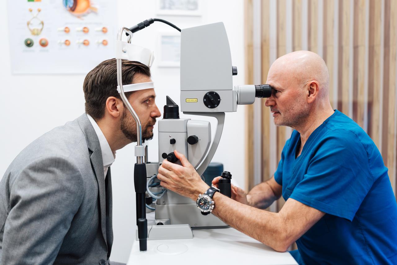 Homem fazendo exame de vista com o médico oftalmologista. É o exame que a pessoa senta e o médico vê o olho do paciente.