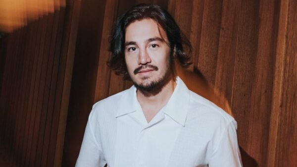 Cantor Tiago Iorc. Homem branco, cabelo preto curto, barba e camisa branca.