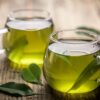 Foto mostra xícaras transparentes de chá verde.