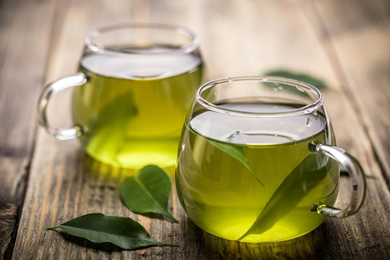 Foto mostra xícaras transparentes de chá verde.