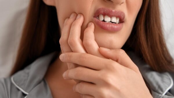 Foto mostra mulher rangendo a boca com dor de dente.