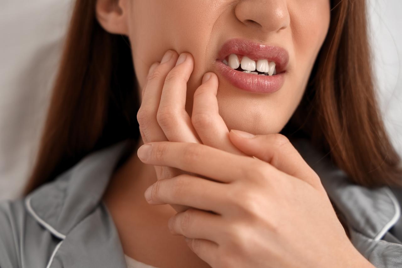 Foto mostra mulher rangendo a boca com dor de dente.