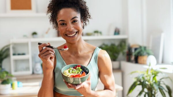 Imagem de uma mulher com roupa de academia se alimentando