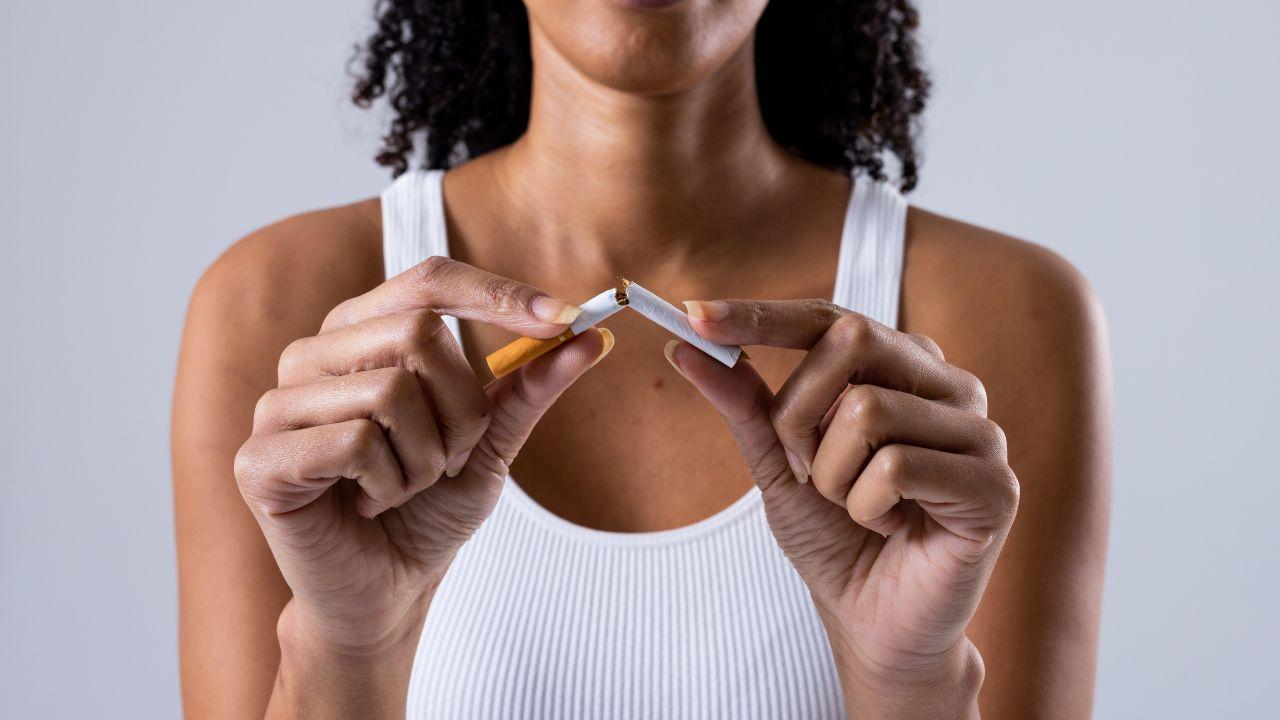 Imagem de uma mulher quebrando um cigarro ao meio