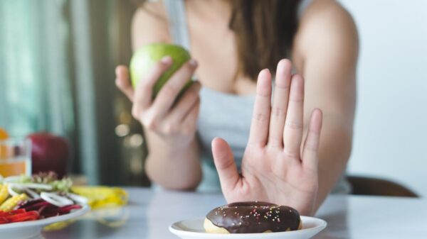 Mulher se recusando a pegar donut, enquanto come comida saudável.