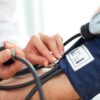 Foto mostra médica aferindo pressão de paciente.