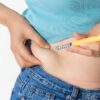 Imagem de uma pessoa aplicando caneta emagrecedora na lateral da barriga