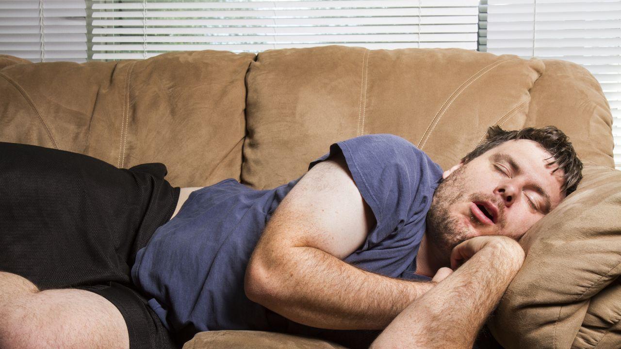 Imagem de um homem cochilando no sofá