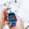 Foto mostra uma mão segurando o aparelho de controle do diabetes indicando que a quantidade de açúcar no sangue está alta.