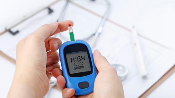 Foto mostra uma mão segurando o aparelho de controle do diabetes indicando que a quantidade de açúcar no sangue está alta.