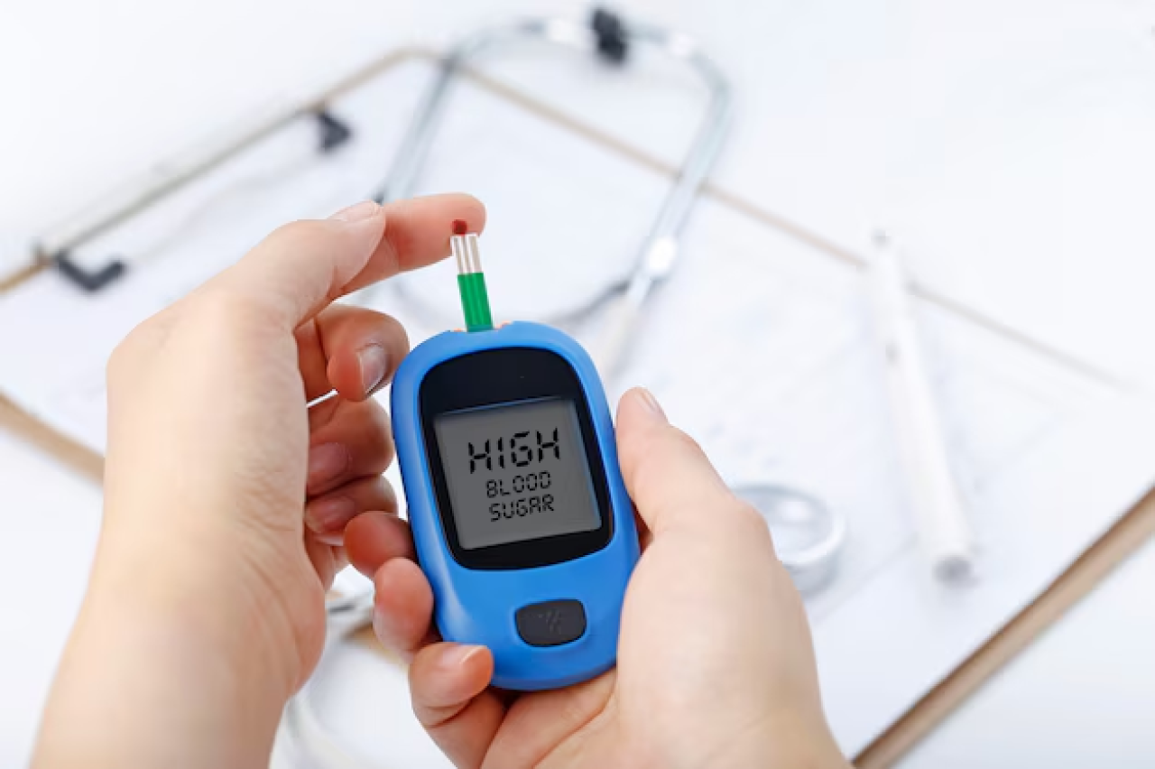 Foto mostra uma mão segurando o aparelho de controle do diabetes indicando que a quantidade de açúcar no sangue está alta.