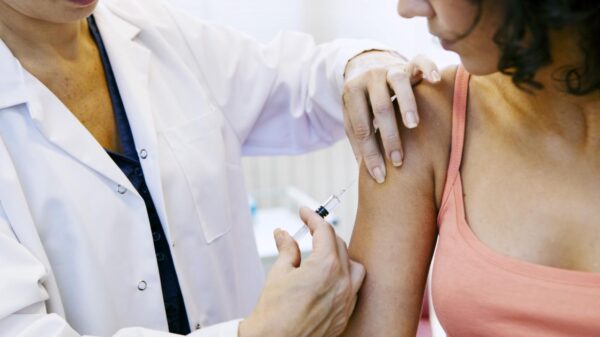 Médica aplicando vacina em braço de paciente.
