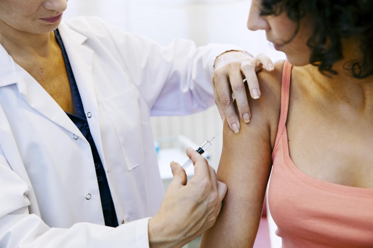 Médica aplicando vacina em braço de paciente.
