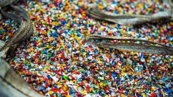 Foto mostra um saco de cheio de microplásticos coloridos.