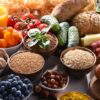 Vários alimentos saudáveis como frutas, legumes e grãos em cima de uma mesa de madeira.